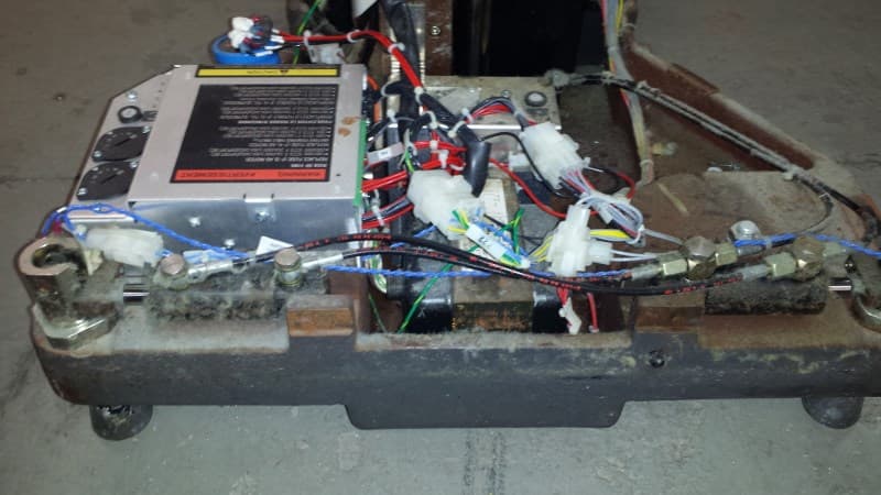 Internal base of a surgical table during rebuild — wiring, hydraulics, and control components inspected and serviced