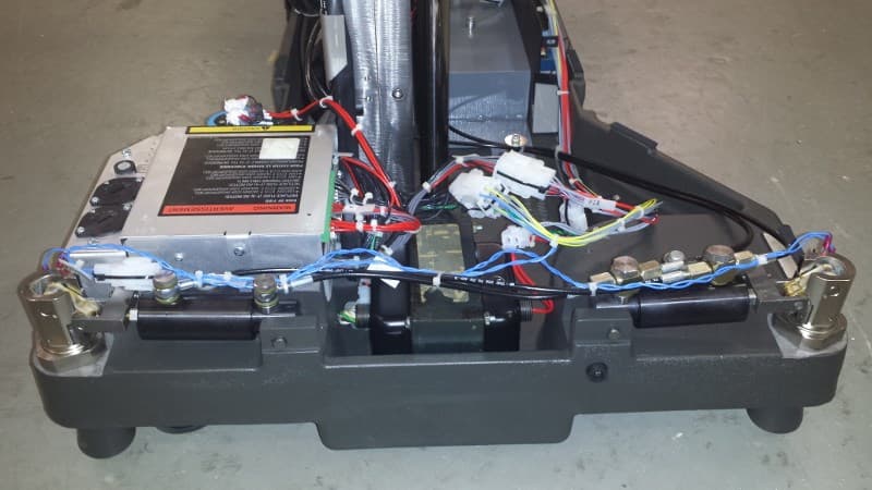 Close-up of a surgical table base being refurbished — electrical harnesses, power supply, and mechanical linkages rebuilt